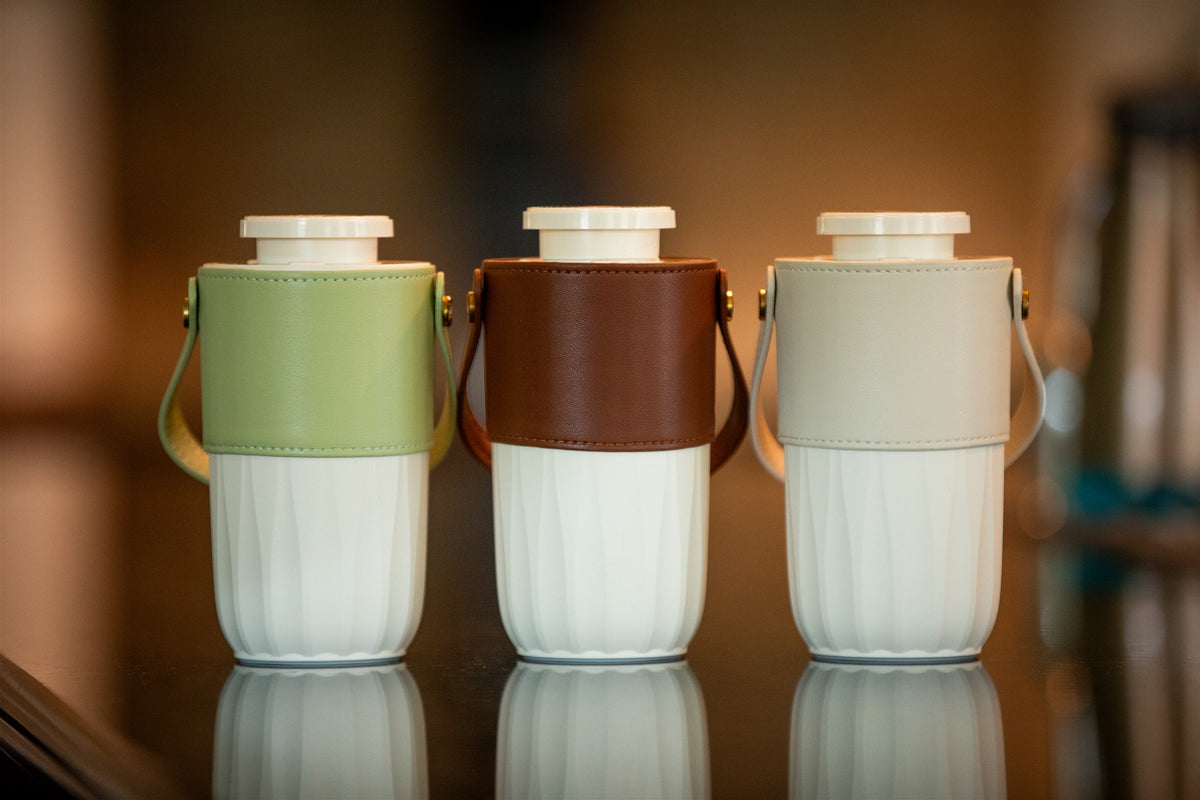 Fresh Aire Car diffusers in green, brown, and beige on a reflective countertop.